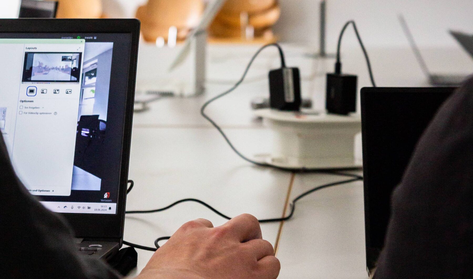 Ein Laptop auf einem Besprechungstisch, verbunden mit Kabeln für eine Internetkonferenz.